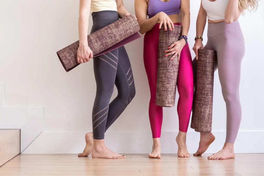 Photo three young woman holding yoga mat in sport wear in white studio yoga teacher workout