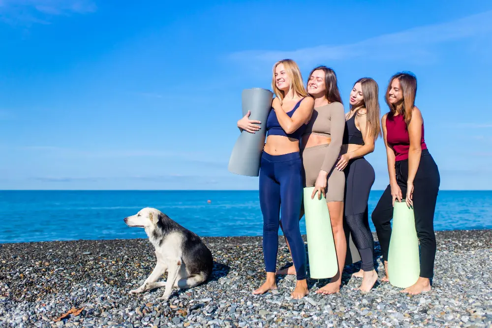 group-young-females-practicing-yoga-seaside.