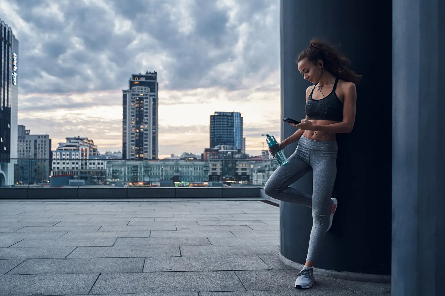 young-athletic-woman-sport-clothes-standing-with-phone-hands-posting-her-training-results-listening-music.