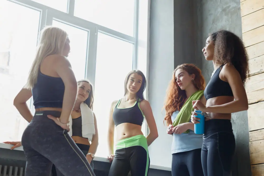 girls-sportswear-chatting-before-fitness-training-group-young-sporty-female-friends-sport-club-pov-active-healthy-lifestyle-concept.