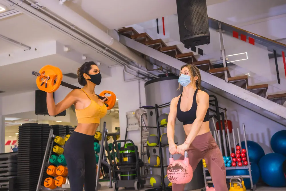 Aprilluck-coronavirus-pandemic-gyms-two-girls-training-with-weights-with-face-masks.