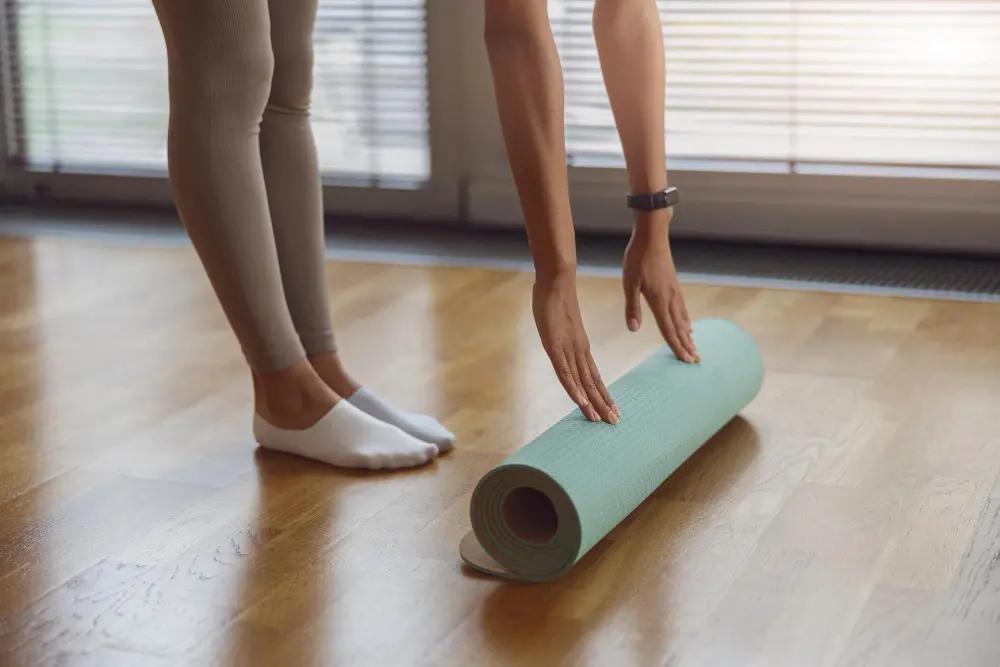 close-up-young-woman-hands-rolling-her-mat-after-yoga-class-wooden-floor